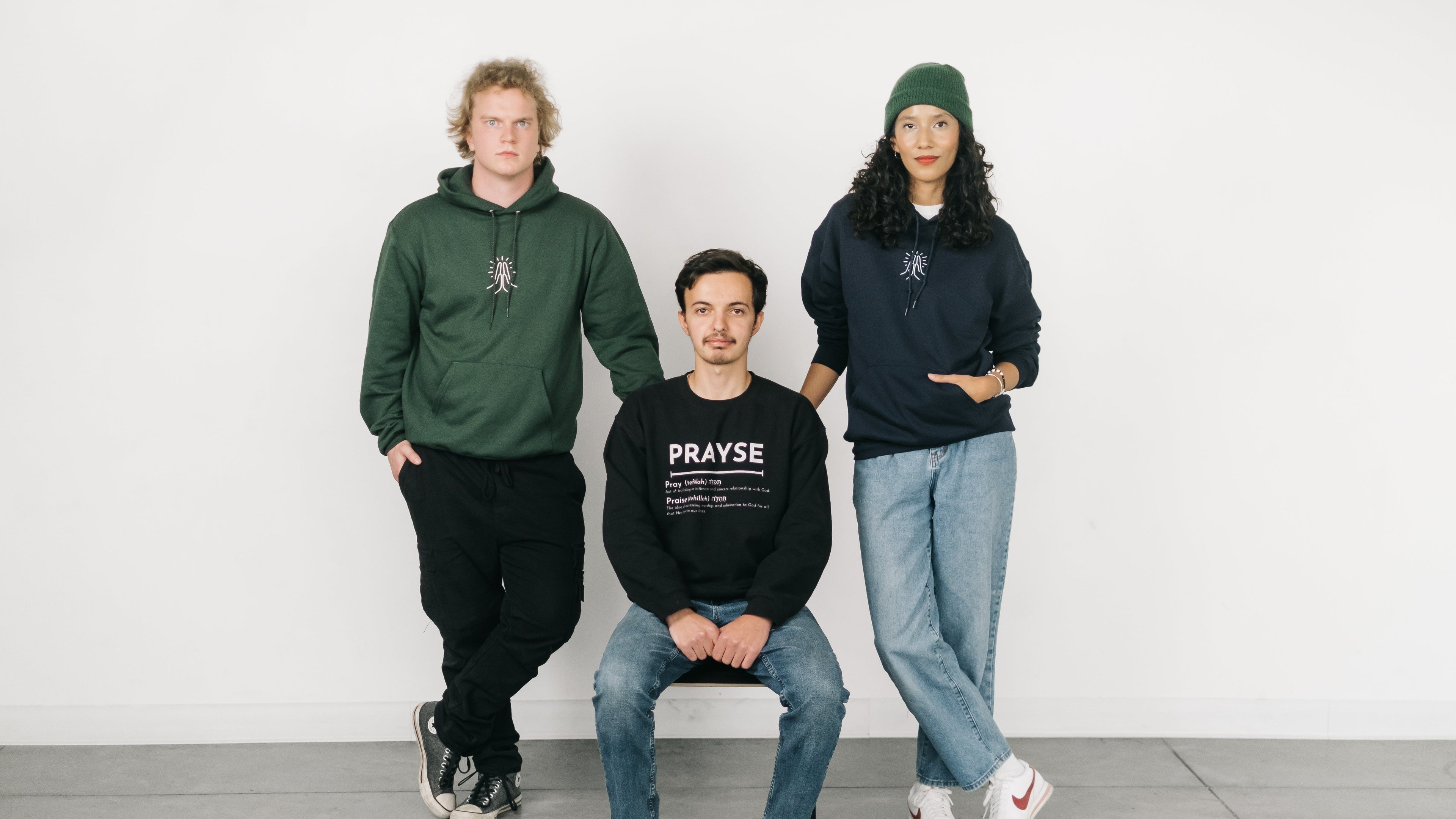 Three people wearing hoodies and sweatshirts with visible branding against a white background